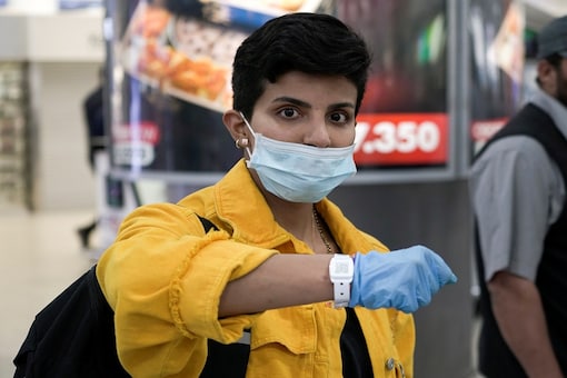 A Kuwaiti woman wearing a protective face mask poses as she shows her quarantine tracking bracelet upon her arrival from Amman to Kuwait Airport, following the outbreak of the coronavirus disease (COVID-19), in Kuwait City. (Reuters)