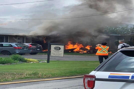 This photo provided by Elwood Delaney shows the scene of a crash involving a Canadian Forces Snowbirds airplane in Kamloops, Canada, Sunday, May 17, 2020. A Canadian acrobatic jet has crashed into the British Columbia neighborhood during a flyover intended to boost morale during the pandemic, killing at least one crew member and setting the house on fire. (Elwood Delaney via AP)