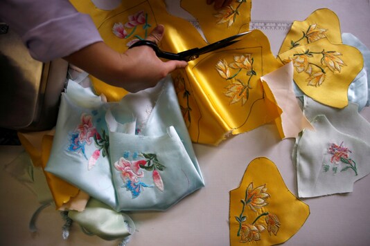A worker cuts patterns off a silk cloth for making face masks designed by Zhou Li, at a studio in Beijing, following the novel coronavirus disease (COVID-19) outbreak, China May 17, 2020. Picture taken May 17, 2020. REUTERS/Tingshu Wang

