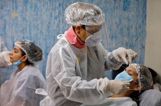 A woman gets her eyebrows threaded by a beautician wearing a protective gear inside a parlor after authorities allowed saloons and beauty parlors to open, during an extended nationwide lockdown to slow the spreading of the coronavirus disease (COVID-19), in Ahmedabad. (Image: Reuters)