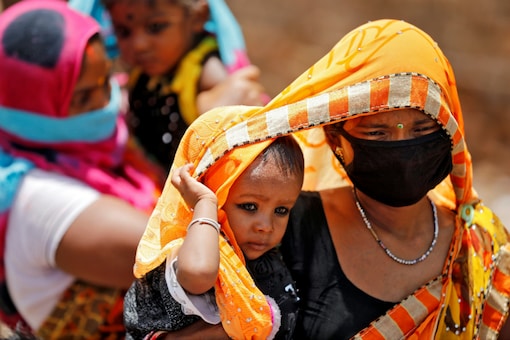 (Representative image) A woman in a mask shields her child from the sun. (Reuters)