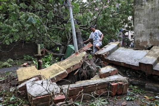 A man walks over a collapsed wall after Cyclone Amphan made landfall in Kolkata on Thursday. (Reuters)