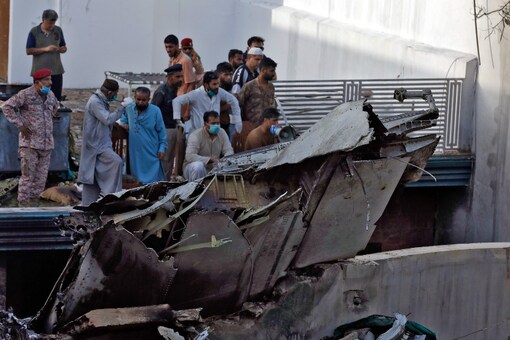 People stand next to the debris of a plane that crashed in a residential area near an airport in Karachi, Pakistan. (Reuters)