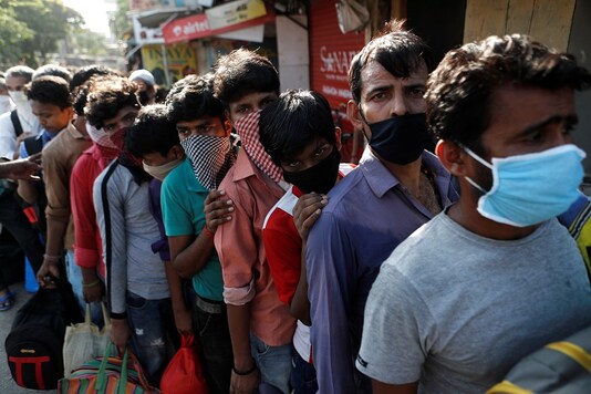 Migrants wearing protective face masks stand in a queue as they wait for transportation in Mumbai. (REUTERS)