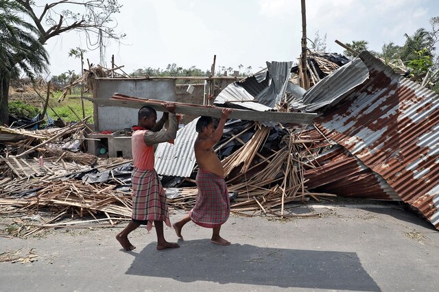 Residents carry tin sheets salvaged from the rubble of a damaged house in the aftermath of Cyclone Amphan, in South 24 Parganas district in West Bengal, India, May 22, 2020. REUTERS/Rupak De Chowdhuri