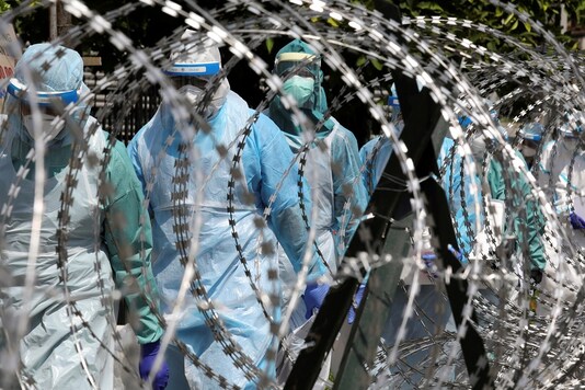 FILE PHOTO: Medical workers wearing protective suits pass by barbed wire at the red zone under enhanced lockdown, amid the coronavirus disease (COVID-19) outbreak