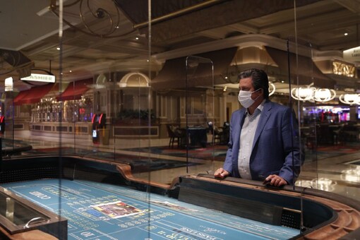 Bill Hornbuckle, acting CEO and president of MGM Resorts International, stands between acrylic barriers used as a coronavirus safety precaution at a craps table in the closed Bellagio hotel and casino, Wednesday, May 20, 2020, in Las Vegas. Casino operators in Las Vegas are awaiting word when they will be able to reopen after a shutdown during the coronavirus outbreak. (AP Photo/John Locher)