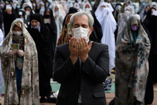Worshippers wearing protective face masks offer Eid al-Fitr prayers outside a mosque to help prevent the spread of the coronavirus, in Tehran, Iran, Sunday, May 24, 2020. (AP Photo/Vahid Salemi)