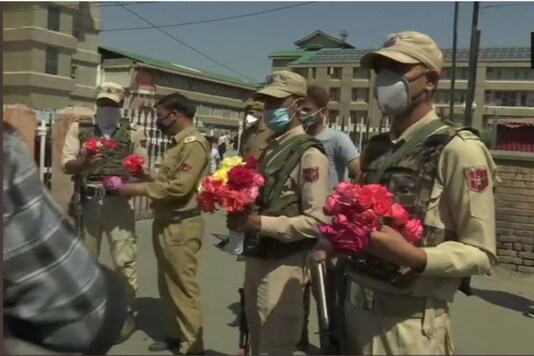 Police personnel with flowers outside hospital in Kashmir.