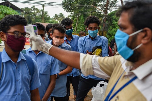 School children wearing masks get their hands sanitized and temperatures checked as they arrive to appear for state board examination during the coronavirus pandemic in Kochi, Kerala state, India, Tuesday, May 26, 2020. (AP Photo/R S Iyer)