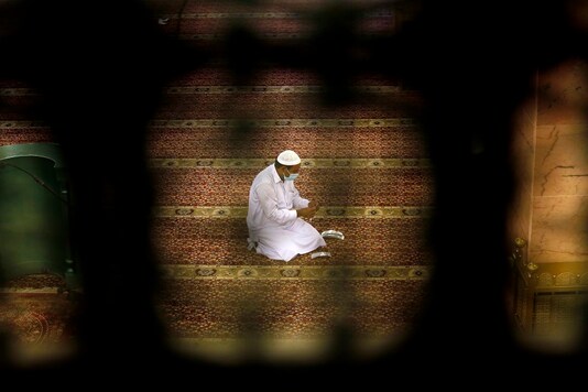 A worker is seen through a window as he places markers to ensure social distancing to help prevent the spread of the coronavirus, at al-Mirabi Mosque in Jiddah, Saudi Arabia. (AP)