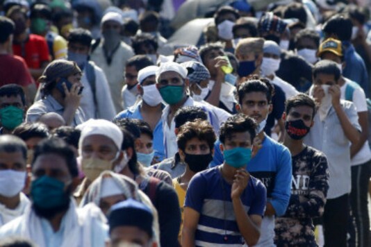 Migrant workers gather for transport to the railway station for their onward journey to their home states, at Dharavi slum in Mumbai. (Image: AP)