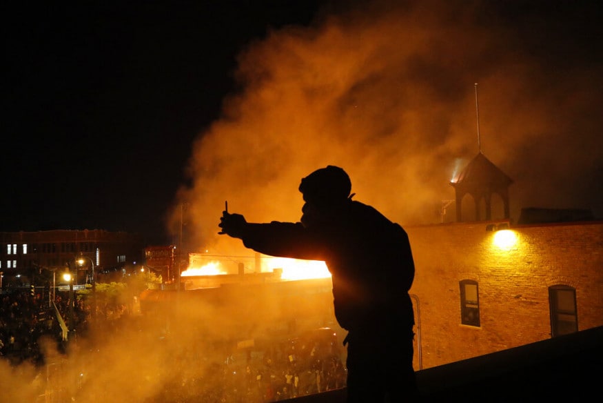  A man makes a video of protesters from the roof of the Minneapolis police 3rd Precinct building, in Minneapolis. (Image: AP)