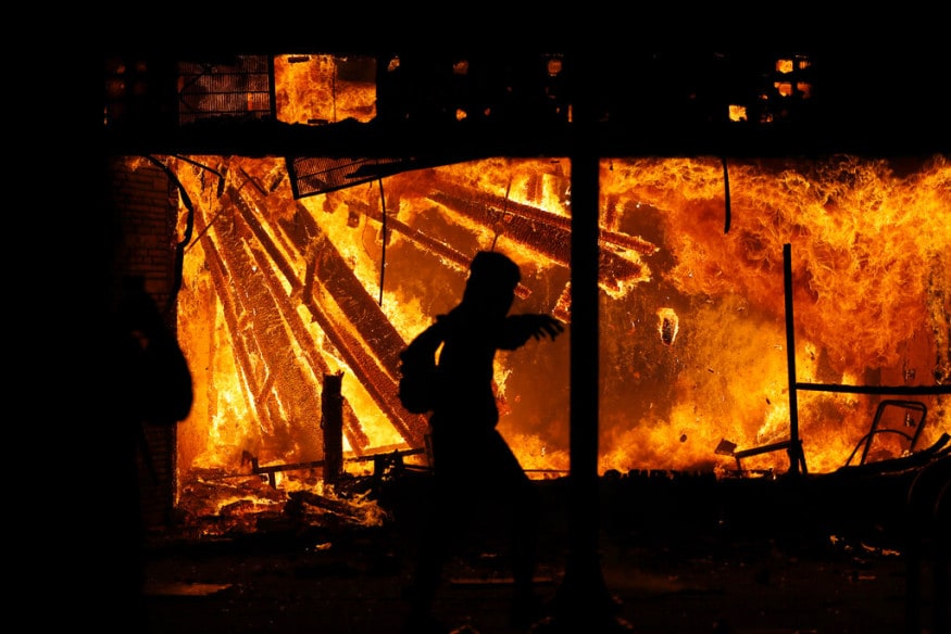  A protester runs in front of the burning 3rd Precinct building of the Minneapolis Police Department, in Minneapolis. (Image: AP)