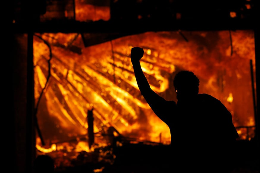  A protester gestures in front of the burning 3rd Precinct building of the Minneapolis Police Department, in Minneapolis. (Image: AP)