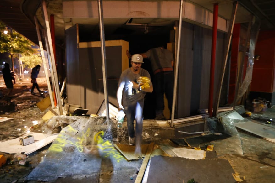  A person takes items from a liquor store, in Minneapolis. (Image: AP)