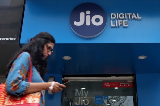 A woman checks her mobile phone as she walks past a mobile store of Reliance Industries' Jio telecoms unit, in Mumbai. (Reuters)
