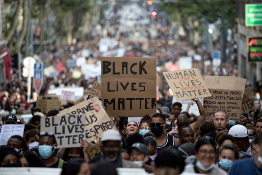 In this representative image, a protester looks up at a sign that reads 
