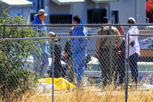 Investigators with the San Luis Obispo County Sheriff-Coronor's office and Paso Robles Police Department investigate a homicide near the Union Pacific railroad tracks north of the train station in downtown Paso Robles, Calif., as law enforcement agencies responded to an early morning shooting in the Central Coast city after a sheriff's deputy was wounded early Wednesday, June 10, 2020. A man has been found fatally shot near where the deputy was wounded after someone opened fire on a police station. The shooter has yet to be found and people in the area are urged to shelter in place. (David Middlecamp/The Tribune of San Luis Obispo via AP