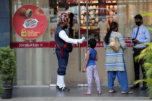 File photo of a security guard checking the temperature of a girl as a precaution outside a store in Bengaluru. (AP)