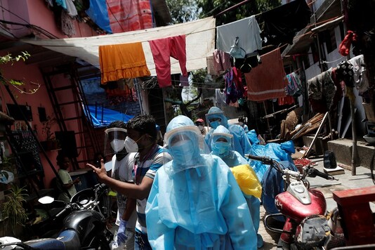 File photo of healthcare workers in personal PPEs and volunteers walking through a slum in Dharavi, Mumbai. (Reuters)