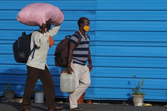 Pedestrians wearing face masks carry their luggage and walk to board trains in Hyderabad on Saturday. (AP)