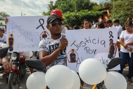Alexander Martínez's friends carry signs that read in Spanish  