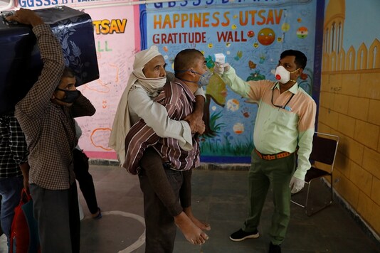 A migrant worker carrying his father on his back has his temperature checked before getting themselves registered for a train to their home state of Uttar Pradesh, during an extended lockdown to slow the spreading of the COVID-19, in New Delhi, India, May 26, 2020. (REUTERS/File)