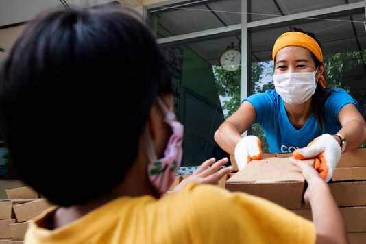 Founder of COVID Thailand Aid, Natalie Bin Narkprasert gives food to a boy at the railway-side community in Bangkok, Thailand | (AP Photo/Sakchai Lalit)