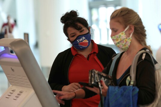 FILE PHOTO: A Southwest Airlines Co. employee wears a protective mask while assisting a passenger at Los Angeles International Airport (LAX) on an unusually empty Memorial Day weekend during the outbreak of the coronavirus disease (COVID-19) in Los Angeles, California, U.S., May 23, 2020. REUTERS/Patrick T. Fallon/File Photo