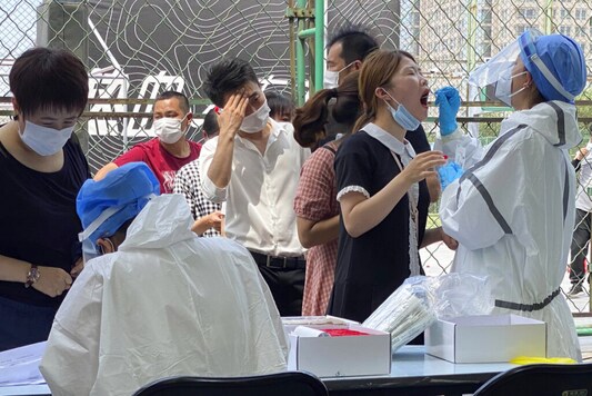 Residents line up to get tested at a coronavirus testing center set up outside a sports facility in Beijing. (Image:AP)