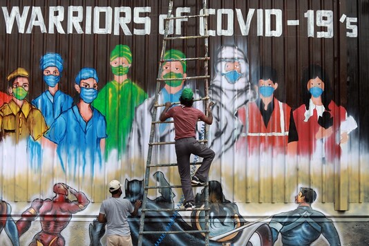 A man gets off a ladder as he completes a mural paying tribute to 'COVID-19 warriors' as India eases lockdown restrictions that were imposed to slow the spread of the coronavirus disease (COVID-19), in New Delhi, India, June 8, 2020. REUTERS/Anushree Fadnavis