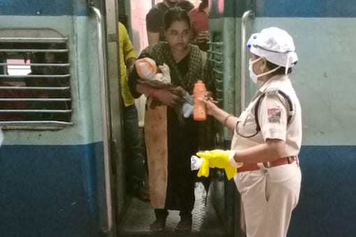 Photograph of the cop handing the bottle of milk to the woman on Shramik Special train.