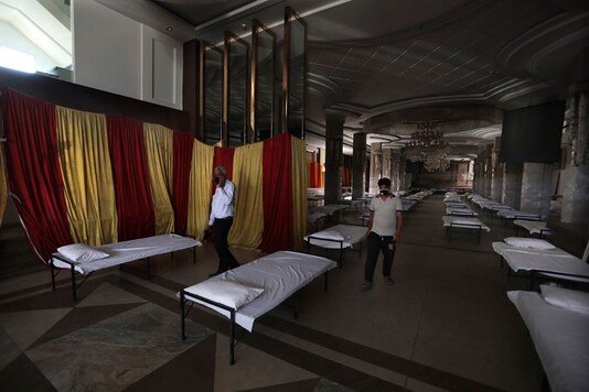 Workers walk across a banquet hall converted into a makeshift coronavirus hospital in New Delhi. (AP Photo/Manish Swarup)