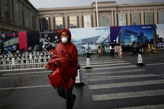 A man wearing a face mask crosses a road near a shopping complex, following a new outbreak of the coronavirus disease (COVID-19) in Beijing, China June 18, 2020. REUTERS/Tingshu Wang