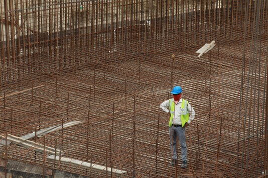 A labourer stands at a construction site after few restrictions were lifted by Delhi government, during an extended nationwide lockdown to slow the spread of the coronavirus disease (COVID-19) in New Delhi, India May 11, 2020. REUTERS/Anushree Fadnavis/File Photo