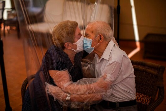 Agustina Cañamero, 81, and Pascual Pérez, 84, hug and kiss through a plastic film screen to avoid contracting the new coronavirus at a nursing home in Barcelona, Spain. (AP)