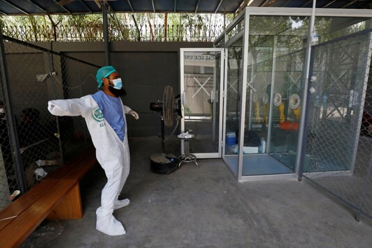 A paramedic puts on personal protection equipment (PPE) before entering a glass booth used for collecting samples to be tested for the coronavirus disease (COVID-19), in Karachi, Pakistan June 23, 2020. REUTERS/Akhtar Soomro