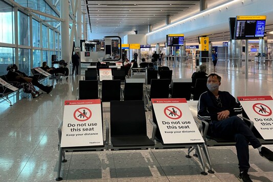 People sit amongst socially-distanced seating signs at Heathrow Airport, as the spread of the coronavirus disease (COVID-19) continues, in London, Britain. (Image Source: Reuters)