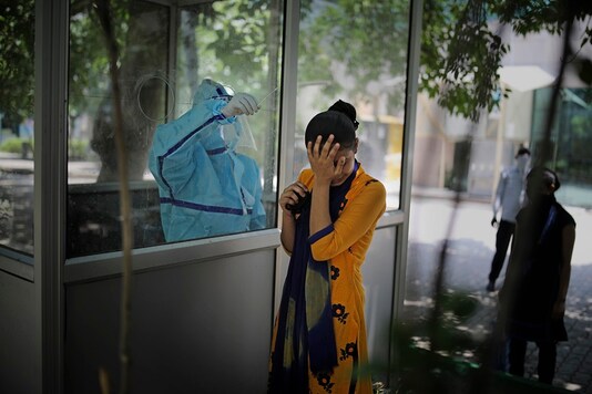 A woman reacts after getting a nasal swab taken to test for the coronavirus in New Delhi. (AP Photo/Altaf Qadri)