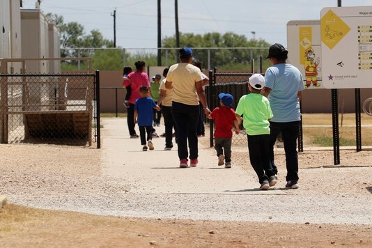 In this August 23, 2019 file photo, immigrants seeking asylum hold hands as they leave a cafeteria at the ICE South Texas Family Residential Center in Dilley, Texas. (AP Photo/Eric Gay, File)