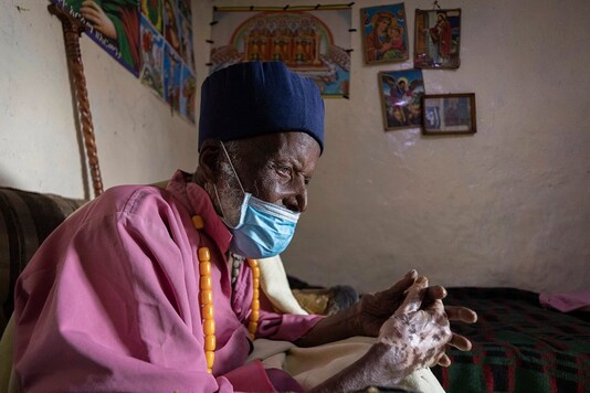 Centenarian Tilahun Woldemichael prays after spending weeks in hospital recovering from the coronavirus, at his house in Addis Ababa, Ethiopia.  (AP Photo/Mulugeta Ayene)