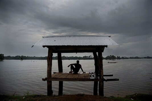 A man sits in a shack next to flood waters in Morigaon district of Assam, India. (AP Photo/Anupam Nath)