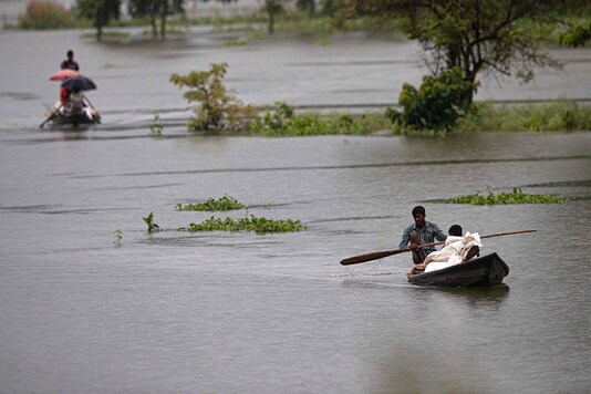 Villagers row country boats with their luggage to move to safer areas through floodwaters in Morigaon district of Assam. (AP)