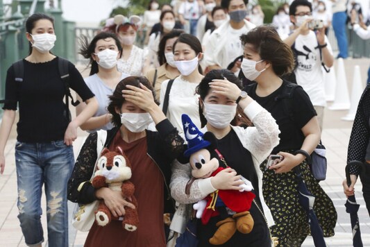 People wearing face masks to protect against the spread of the new coronavirus walk toward the entrance to Tokyo Disneyland in Urayasu, near Tokyo. (Image: AP)
