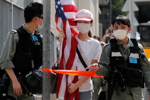 A protester carrying an American flag as she is stopped by riot police during a protest outside the U.S. Consulate in Hong Kong, Saturday, July 4, 2020 to mark the American Independence Day or "the Fourth of July." (AP Photo/Kin Cheung)