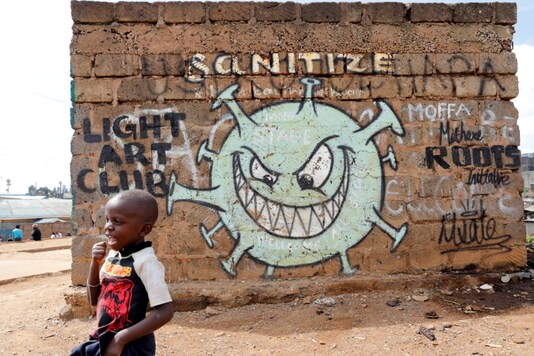 FILE PHOTO: A boy stands in front of a graffiti promoting the fight against the coronavirus disease (COVID-19). (Reuters)