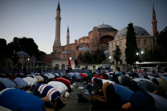 Muslims offer their evening prayers outside the Byzantine-era Hagia Sophia, one of Istanbul's main tourist attractions in the historic Sultanahmet district of Istanbul, following Turkey's Council of State's decision, Friday, July 10, 2020. (AP Photo/Emrah Gurel)
