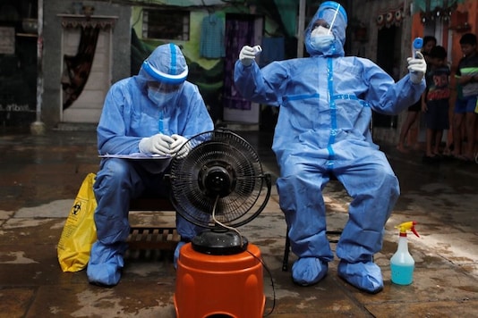 Healthcare workers rest in front of a fan during a check up campaign for the coronavirus disease (COVID-19) at a slum area in Mumbai, India July 8, 2020. REUTERS/Francis Mascarenhas
