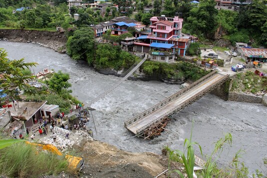 People gather near the bridge that is damaged due to the flood at Raghu Ganga River in Myagdi, Nepal.  REUTERS/Santosh Gautam